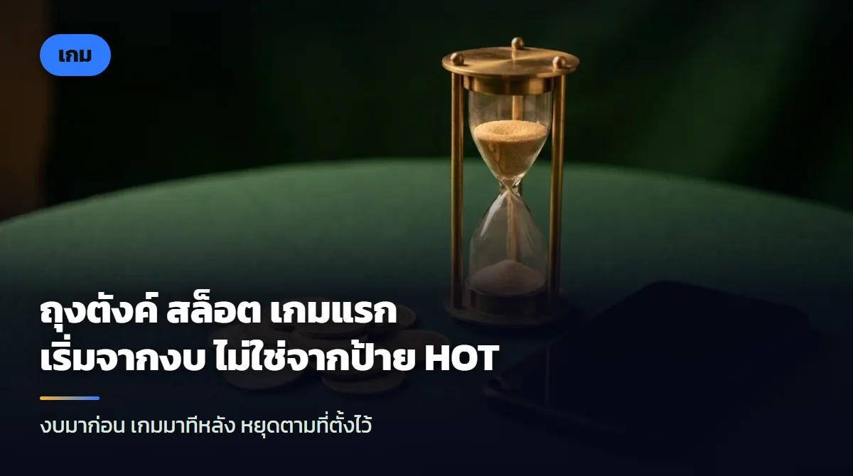 เหรียญทองกองเล็กสามกองเรียงจากต่ำไปสูงบนโต๊ะสีกรมท่า ข้างนาฬิกาทรายและสมาร์ตโฟนจอมืด ใต้แสงไฟสีอุ่น